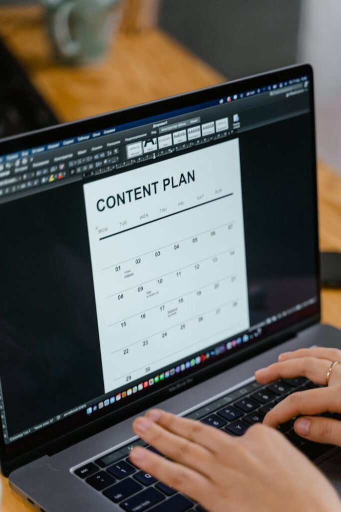 The Art of Drawing Readers In: Your attractive post title goes here Close-up of hands typing on a laptop displaying a content plan document, ideal for business or marketing content.
